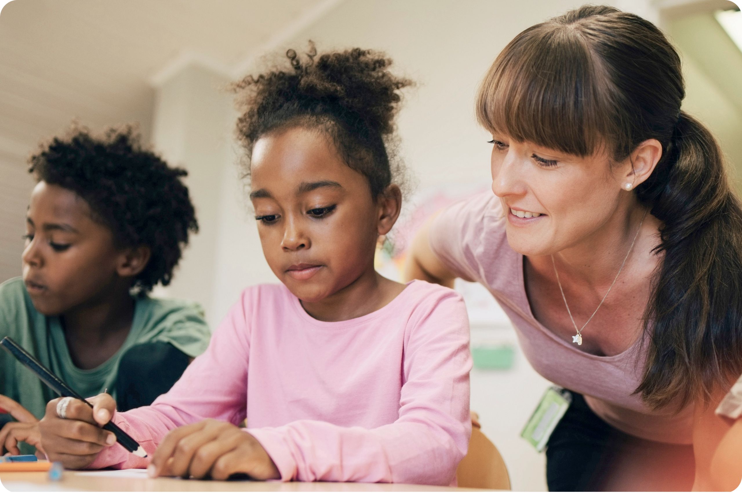 Students are sitting at the desk, and the teacher is helping Students are sitting at the desk, and the teacher is helping