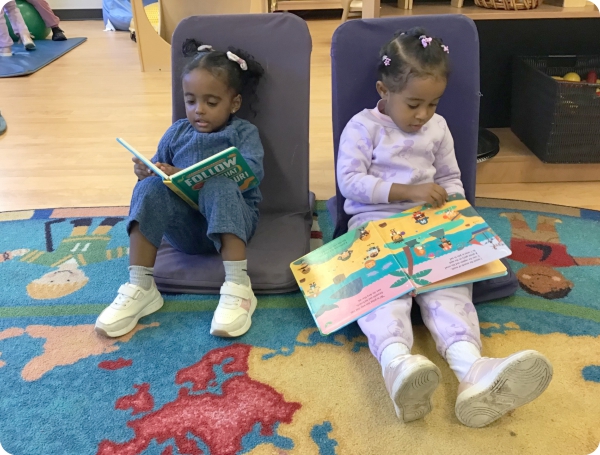 Children seated at a carpet reading books